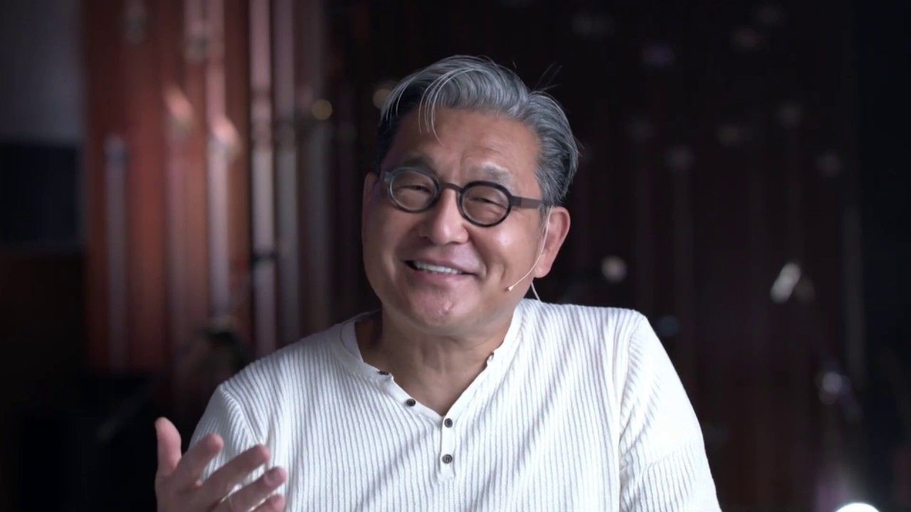 Smiling man in glasses and a white shirt with a microphone headset.